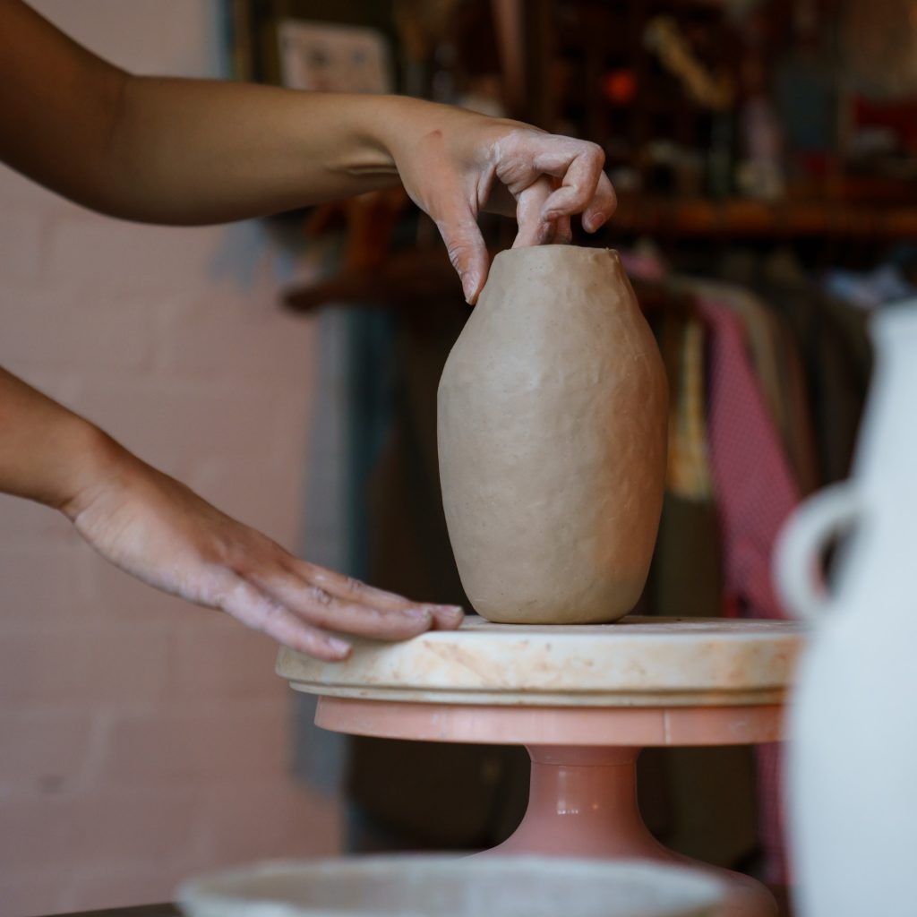 Pottery creation: female artist shaping sculpturing potter vase of raw clay. Girl artisan at work